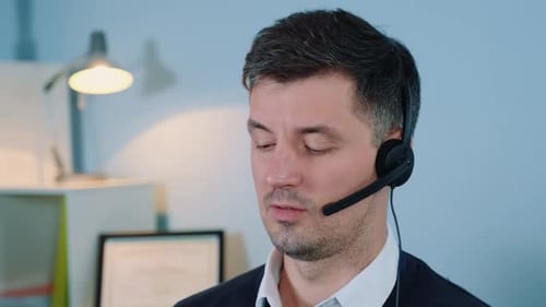 Primer plano de un agente de un centro de llamadas caucásico hablando con auriculares en el teléfono