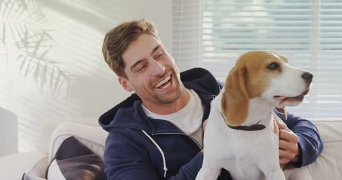 Man Laughing While Holding Beagle Dog Indoors