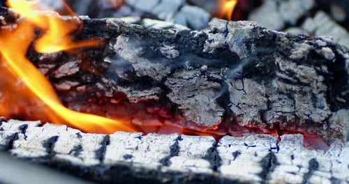 Les charbons brûlent dans de vives flammes avec de la fumée