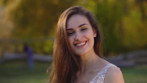 Portrait of Beautiful Brunette Woman with Long Hair Is Having Fun in Sunny Rays at Autumn Park