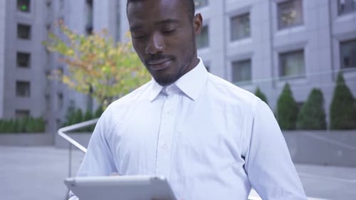 Portrait of Handsome African American Man in White Shirt Working with the Tablet Standing on