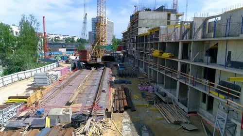Flying over construction site towards tower crane with construction materials