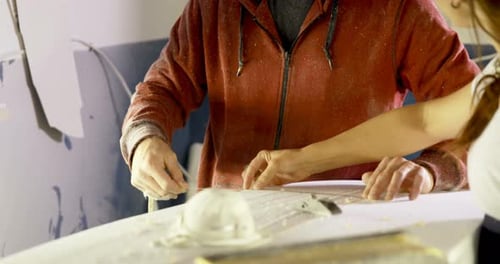 Man and woman interacting with each other while making surfboard 4k