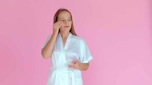 Woman Applies Beauty Eye Patches in Satin Robe