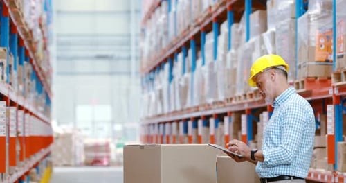 Employé d'entrepôt utilisant une tablette numérique lors du contrôle des colis