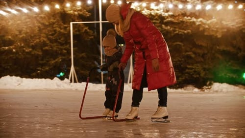 A Young Woman Skating on the Ice Rink with Her Little Daughter - Skating with Hockey Goal