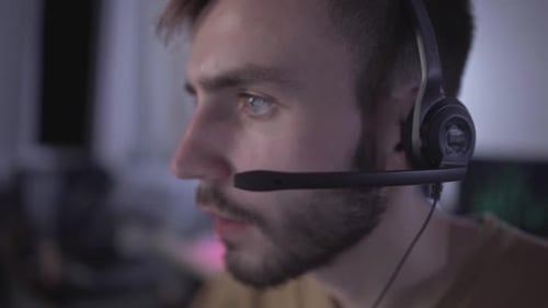 Gesicht eines absorbierten nervösen Spielers im Headset, der Videospiele online spielt. Seitenansicht-Porträt eines Süchtigen