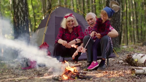 Family Camping and Roasting Sausages by Campfire