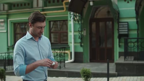 Closeup Man Using Earphones. Businessman Walking with Earphones at Street