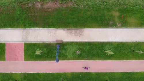 Drohnenaufnahme einer sportlichen Radfahrerin auf dem Fahrrad im Sommer. Glückliche Radfahrerin fährt mit dem Fahrrad.