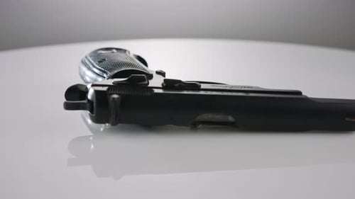 Waffenkontrolle. Studioaufnahme einer 9-mm-Pistole, die sich auf einer reflektierenden Oberfläche dreht
