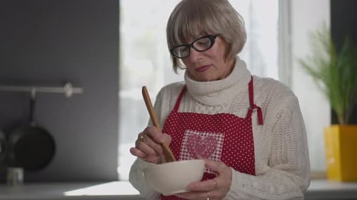 Gray Haired Woman Prepares Food in Kitchen