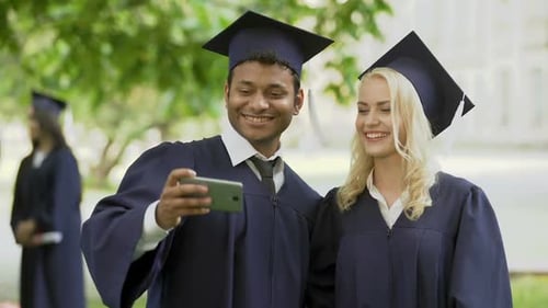 College Friends in Academic Regalia Taking Photo with Cellphone and Checking It