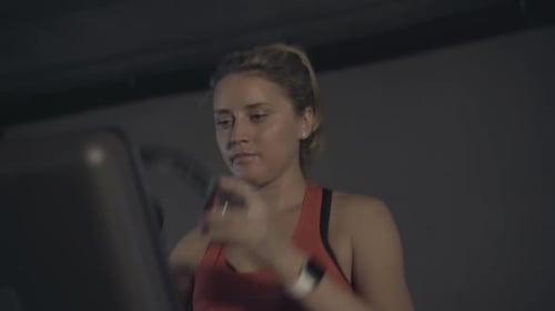 Blonde Woman Jogging on Treadmill Wearing Headphones