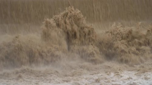 Muddy Water Rushing Over Spillway