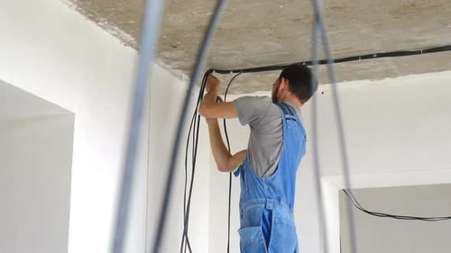 Electrician Installing Wires in Unfinished Interior
