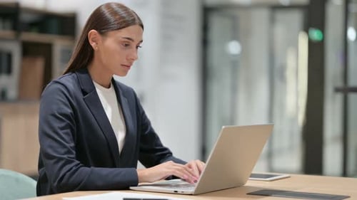 Woman Smiling Working on Laptop in Modern Office