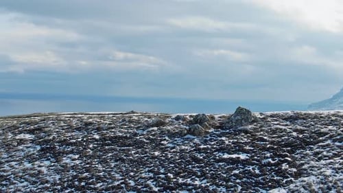 Person Running on Snowy Hilltop Towards Coast
