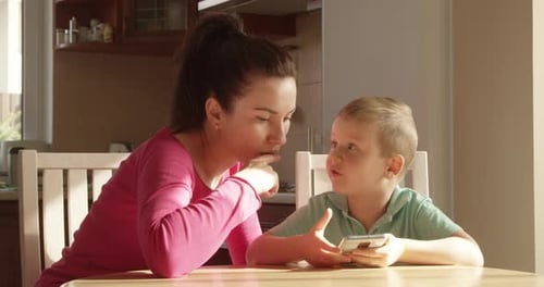 Woman and Child at Table Using Smartphone