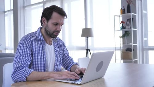 Man Typing on Laptop Shows Exaggerated Shock