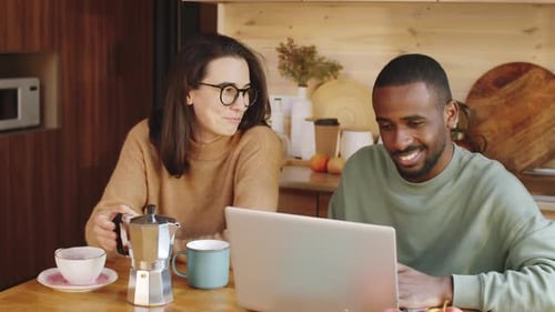 Couple Works On Laptop and Drinks Coffee at Table