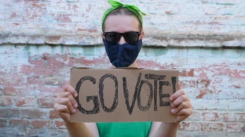 Woman shows cardboard Go Vote sign Voting balloting polling Political choice elections voice 4K