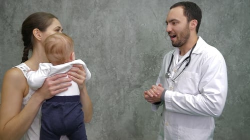 Boy with Mother at Pediatrician's Office Talking to A Doctor.