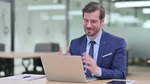 Man in Suit on Laptop Video Call in Office