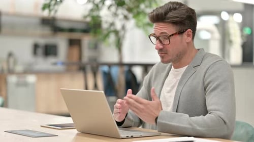 Middle Aged Man Doing Video Chat on Laptop in Office