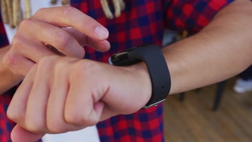 Mixed race man with dreadlocks standing in the street using smartwatch
