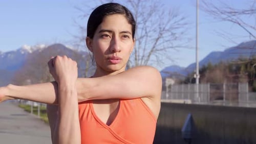 Woman Stretching Arms in Sunny Park on Clear Day
