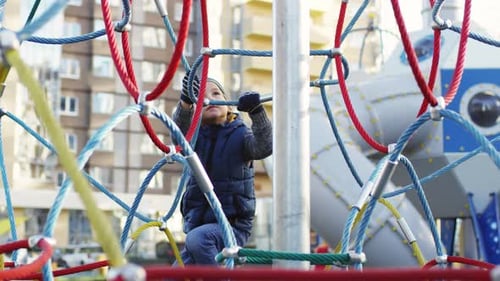 5-Year-Old Caucasian Boy Climbing down Rope Structure on Playground