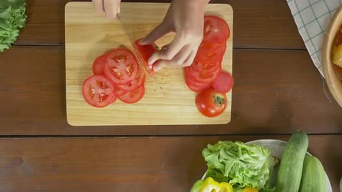 Woman Slicing Tomato on Wooden Cutting Board