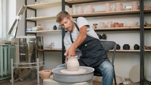 Man Shaping Clay on Pottery Wheel in Studio