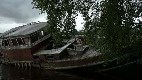 Derelict Boat Sits on Lake, Surrounded by Nature