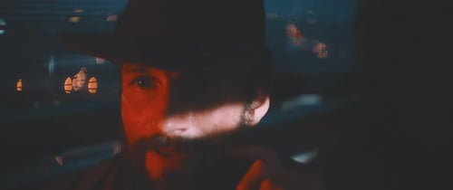 Close up of man waving through shutter and red lights using vintage camera