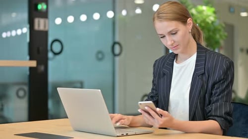 Woman Working at Desk with Laptop and Phone