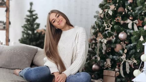 Woman Smiling by Christmas Tree in Home