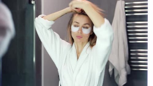 Woman in Robe Styling Hair in Bathroom