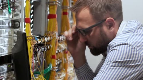 Man Works Diligently at Computer in Server Room