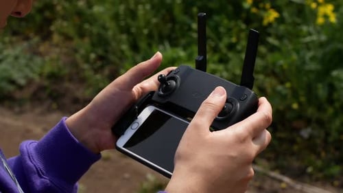 Remote control of the drone in the close-up. Women controlling flying drone for aerial view.