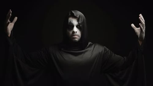 Mysterious Hooded Figure Raising Arms in Dark