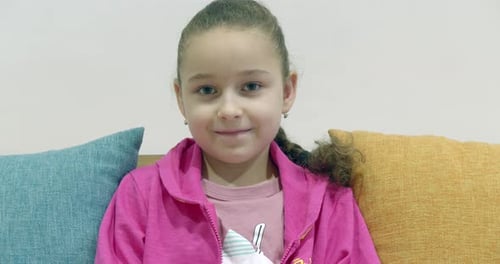 Smiling Young Girl Sitting Indoors on Couch
