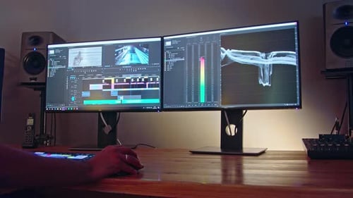 Editor de vídeo sentado en una suite de edición oscura trabajando en un proyecto de vídeo