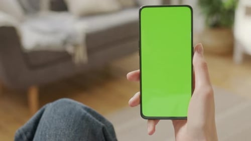 Back View of Woman Holding Chroma Key Green Screen Smartphone Watching Content Without Touching or