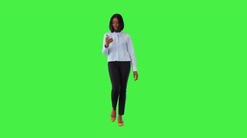Woman Walks and Looks at Phone on Green Screen