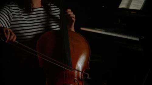 Woman Playing Cello With Piano in Dark Room