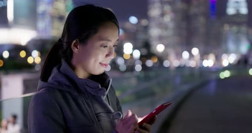 Woman Using Smartphone in City at Night