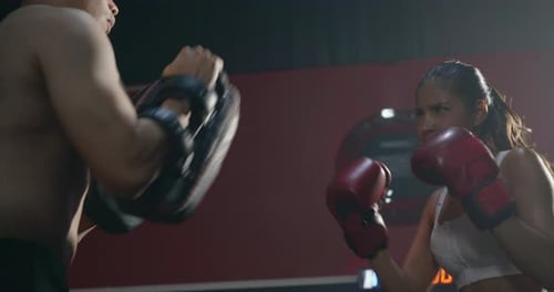 Woman Boxer Punches Pads with Trainer in Gym