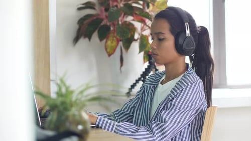 Young Woman Working at Laptop Wearing Headphones